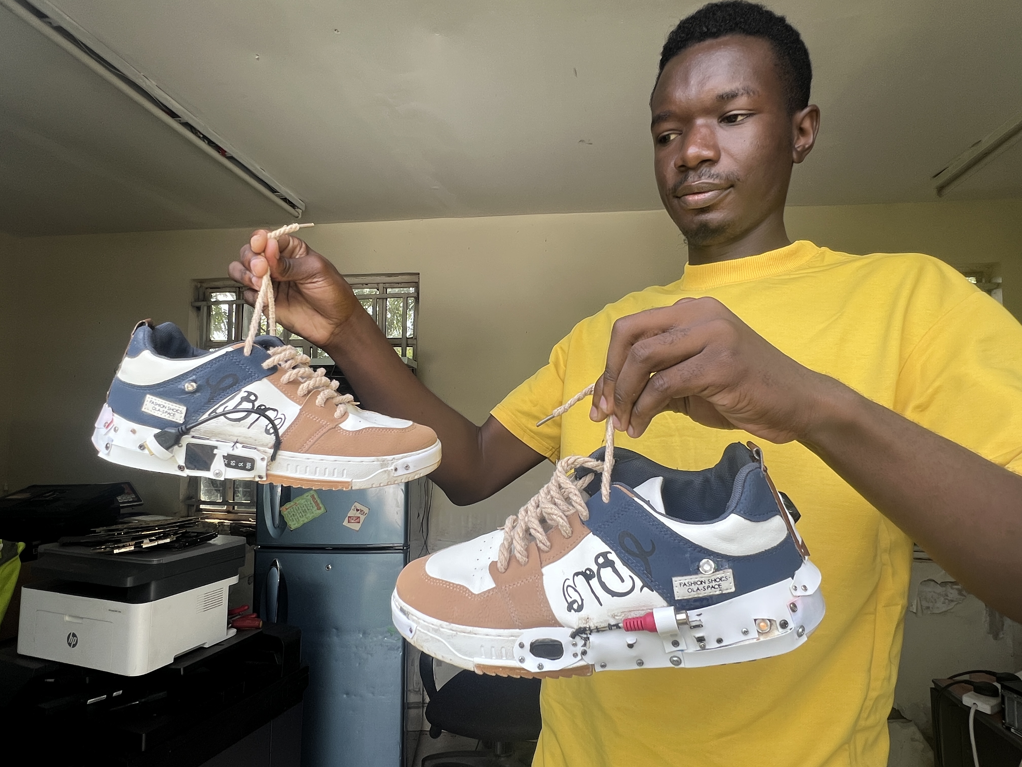 Teddy Omondi holding his robotic shoes